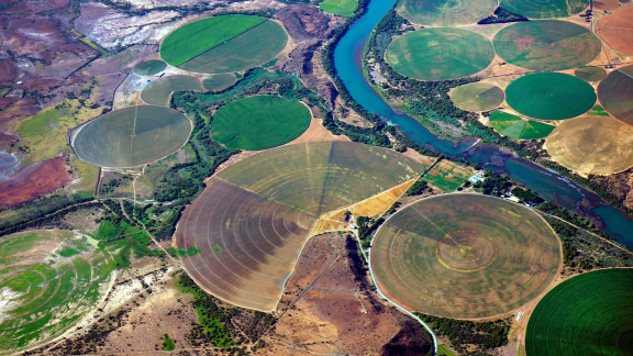 Ilmakuva ympyränmuotoisista kastelualueista, joiden keskellä näkyy joki.