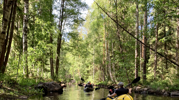 Kuvassa näkyy kaksi kajakkia jokimaisemassa.