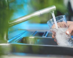 Juomavesi valuu hanasta juomalasiin.