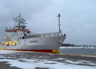 Valot tutkimusalus Arandan kannelta loistavat harmaaseen talviaamun laiturimaisemaan tammikuussa 2026.