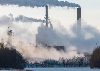 Maisemakuva savupiipuista, jotka tupruttavat paljon savua. 