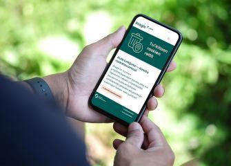 Matkapuhelinta pitelevät kädet.