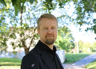 Kuvassa on Syken ilmastoratkaisut-yksikön kehittämispäällikkö Sampo Soimakallio. Taustalla on kesäinen pihamaisema.