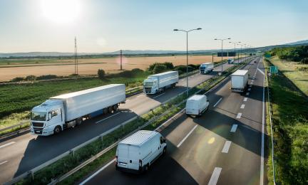 Valkoisia rekkoja ajaa aurinkoisena päivänä.