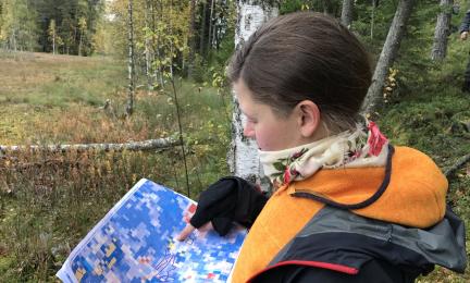 Henkilö katsoo värikästä karttaa luonnossa. A person looking at a colourful map in nature