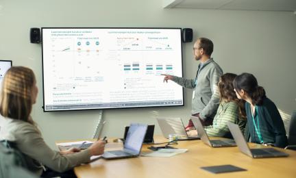 Ihmiset katsovat diaesitystä kokouksessa.