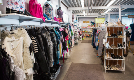 Käytettyjä vaatteita henkareissa rekeissä ja kenkiä hyllyissä kierrätyskeskuksessa