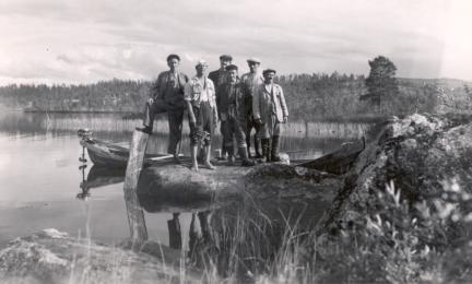 A group of hydrologists standing on a rocky shoreline at Lake Ounasjärvi in 1949.