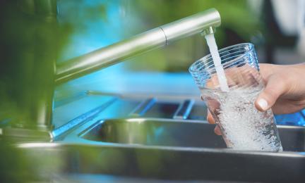 Juomavesi valuu hanasta juomalasiin.