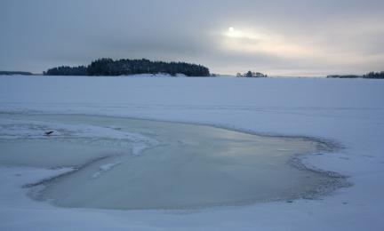 Luminen talvimaisema, jossa keskellä lähes sula virtauskohta.
