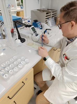 Kuvassa tutkija valkoisessa takissa mittaa pH:ta näytteestä